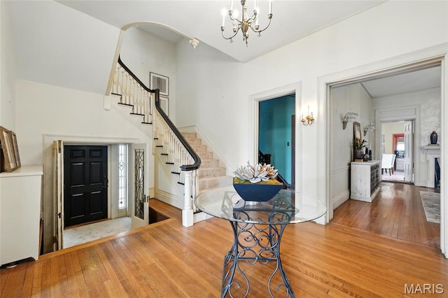 entryway featuring hardwood / wood-style flooring, stairs, a chandelier, and baseboards