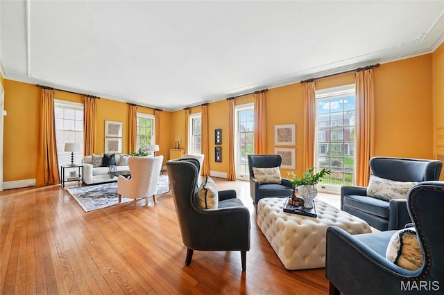 living room featuring hardwood / wood-style flooring, crown molding, and baseboards