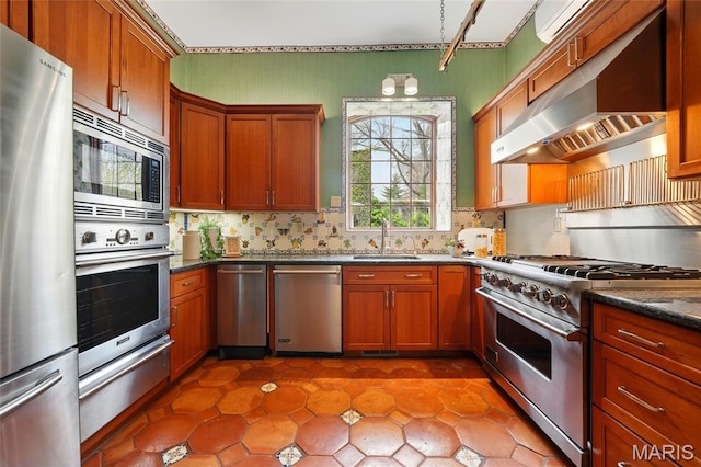 kitchen featuring stainless steel appliances, a sink, under cabinet range hood, a warming drawer, and tasteful backsplash