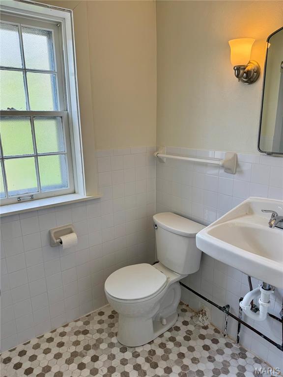 bathroom featuring tile walls, toilet, tile patterned floors, and wainscoting