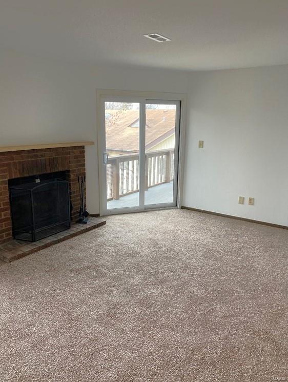 unfurnished living room featuring a brick fireplace, carpet, and baseboards