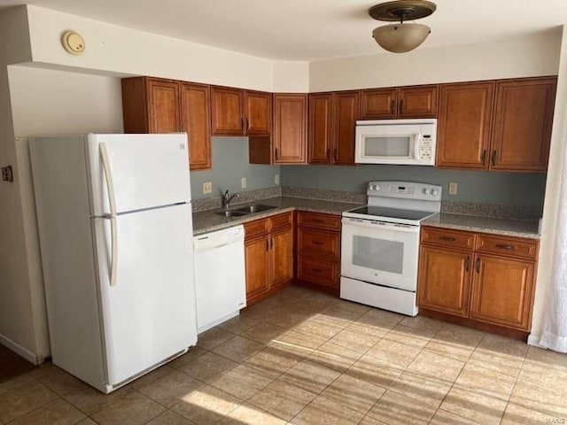kitchen featuring white appliances, a sink, brown cabinets, and light tile patterned floors