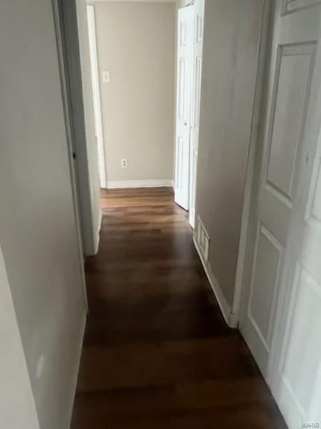 corridor with dark wood finished floors and baseboards