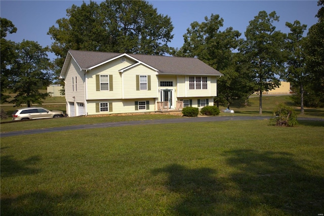 bi-level home with a front lawn, an attached garage, and driveway