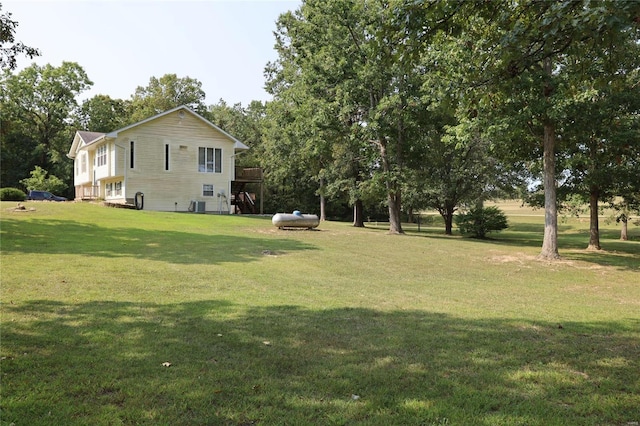 view of green lawn featuring central AC and a wooden deck