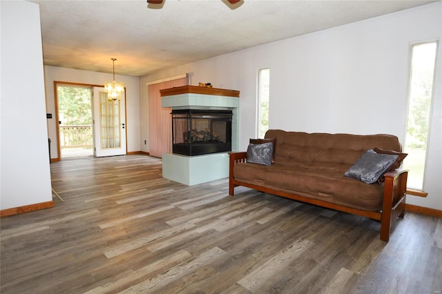 living area featuring wood finished floors, baseboards, ceiling fan, a chandelier, and a tile fireplace