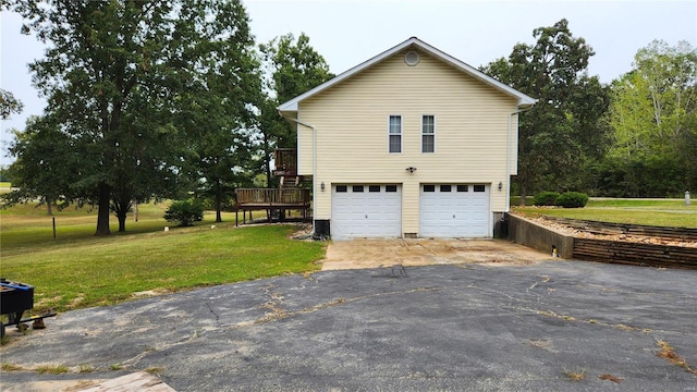 view of property exterior featuring driveway, a garage, a yard, and a wooden deck