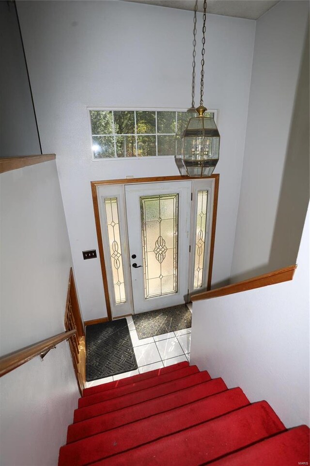 foyer with stairway, a chandelier, tile patterned flooring, and a towering ceiling
