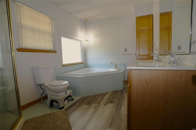bathroom featuring a bath, toilet, vanity, a stall shower, and wood finished floors