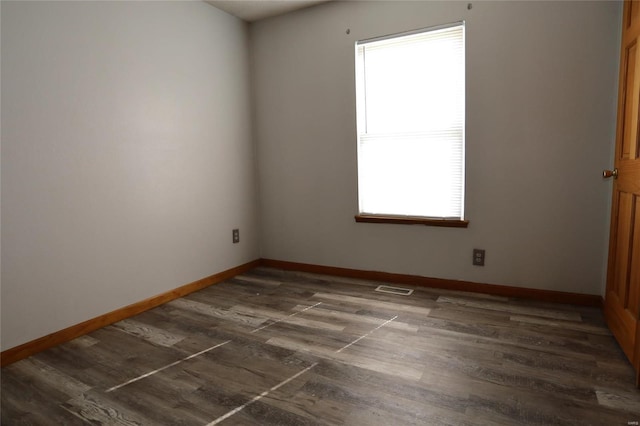 spare room featuring healthy amount of natural light, baseboards, and dark wood-style flooring