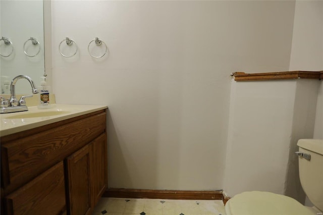 half bath featuring toilet, vanity, and baseboards