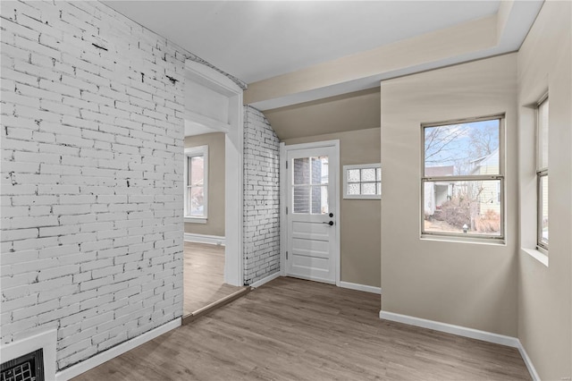 4634 Tyrolean Ave, Saint Louis, MO 63116 - foyer featuring baseboards, wood finished floors, brick wall, and vaulted ceiling