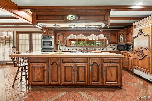 3112 Parkview Dr, Granite City, IL 62040 - kitchen with a kitchen island with sink, decorative backsplash, double oven, brick flooring, and beamed ceiling