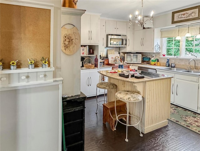 520 N Main St, Louisiana, MO 63353 - kitchen featuring stainless steel microwave, a center island, light countertops, a chandelier, and white cabinetry