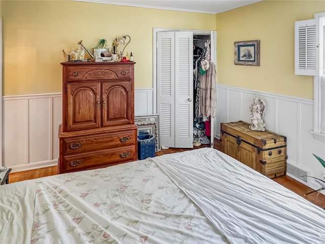 520 N Main St, Louisiana, MO 63353 - bedroom with a closet, a wainscoted wall, a decorative wall, wood finished floors, and ornamental molding