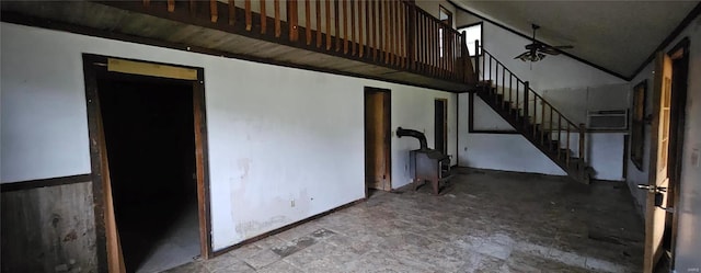 unfurnished living room featuring stairs, a ceiling fan, and baseboards