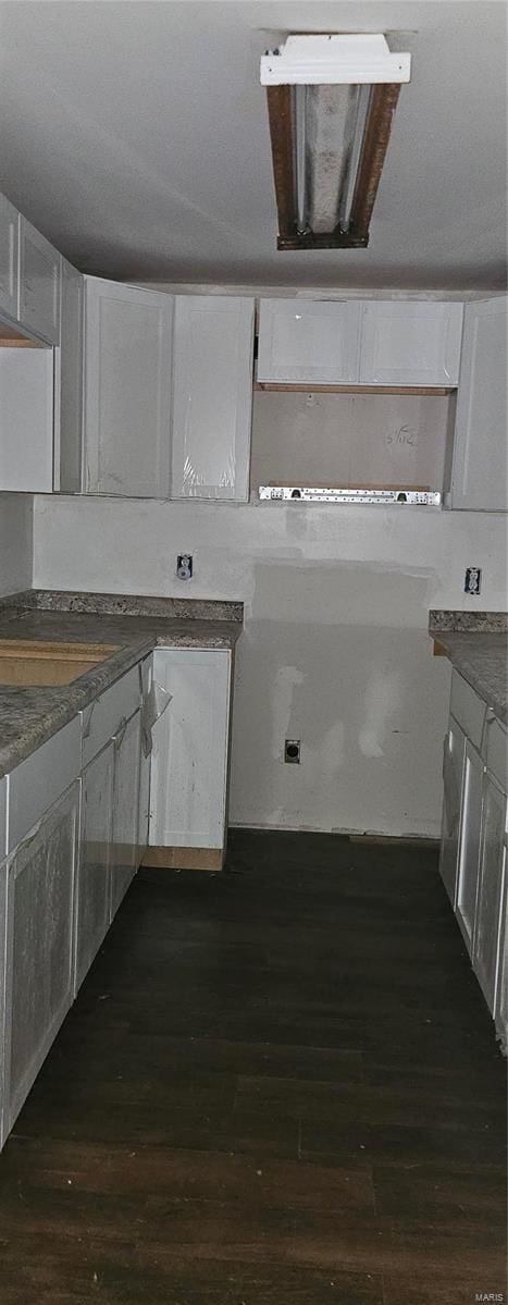 kitchen featuring dark wood-style flooring, dark countertops, and white cabinetry