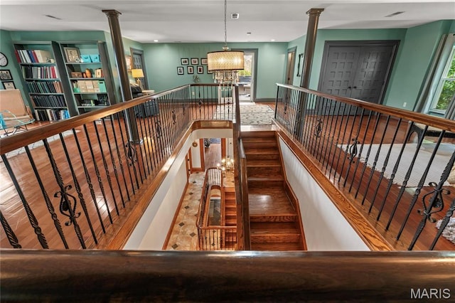 3623 Ohio Ave, Saint Louis, MO 63118 - stairway featuring decorative columns, healthy amount of natural light, wood finished floors, and a chandelier