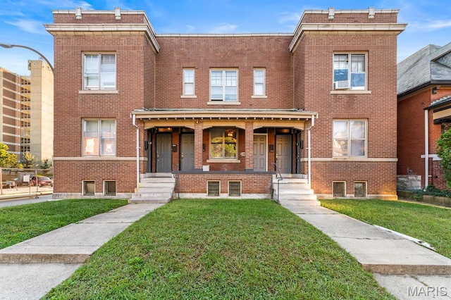 view of front of property with a porch, brick siding, and a front lawn