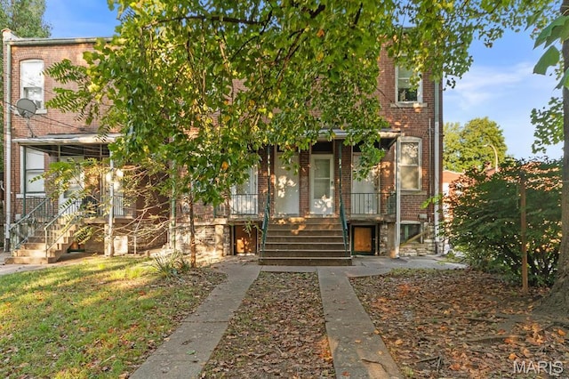 multi unit property featuring stairs, brick siding, and a porch