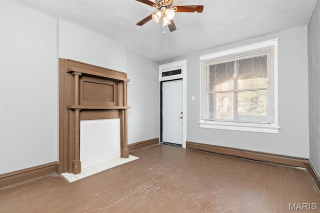 unfurnished living room featuring a ceiling fan, a baseboard heating unit, baseboards, and wood finished floors