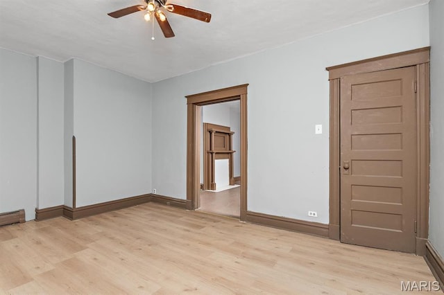 empty room featuring light wood finished floors, ceiling fan, and baseboards