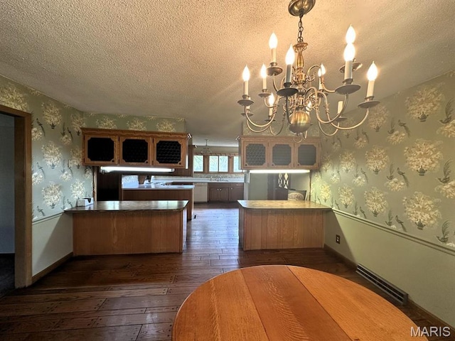 16347 Crestview Dr, Dexter, MO 63841 - kitchen featuring dark wood finished floors, a peninsula, a textured ceiling, glass insert cabinets, and a chandelier