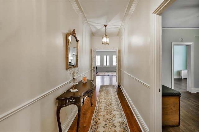 hallway with ornamental molding, dark wood finished floors, a chandelier, and baseboards