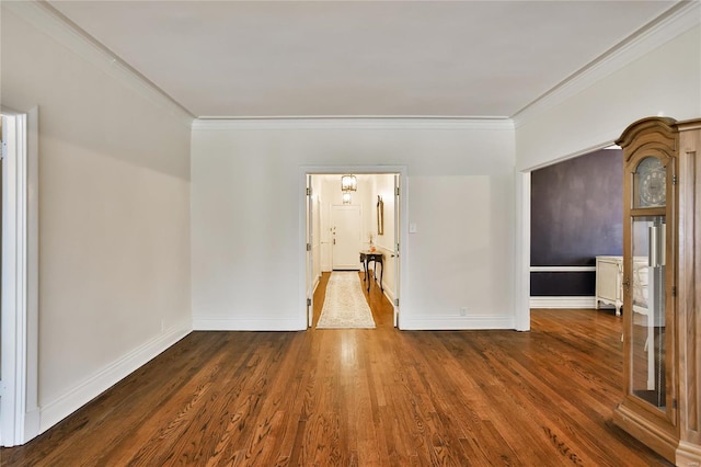 empty room featuring wood finished floors, ornamental molding, and baseboards
