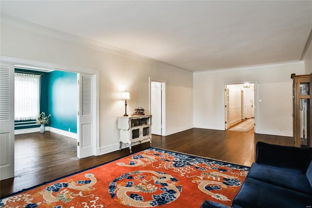 living room featuring wood finished floors, ornamental molding, and baseboards