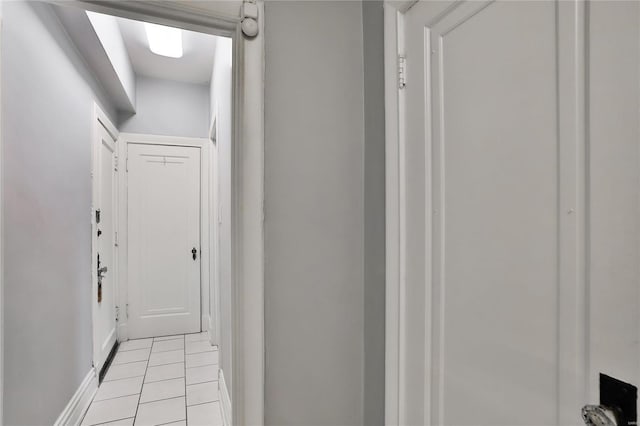 hallway featuring light tile patterned floors and baseboards