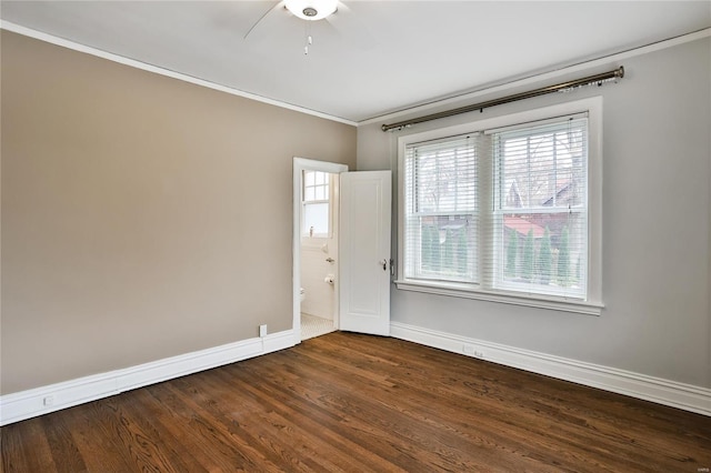 empty room with crown molding, baseboards, dark wood-type flooring, and ceiling fan