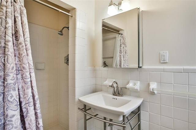bathroom with tiled shower, a sink, and tile walls