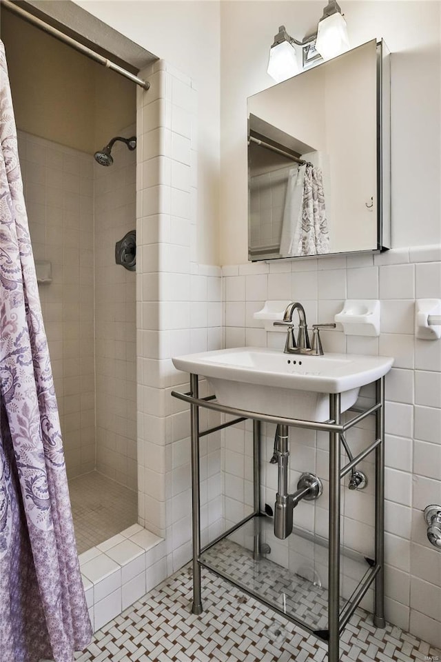 full bathroom with tile walls, a tile shower, a wainscoted wall, and tile patterned flooring