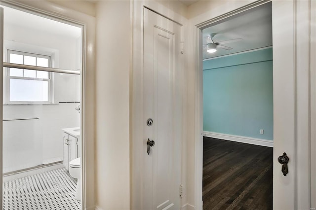 corridor featuring baseboards and wood finished floors