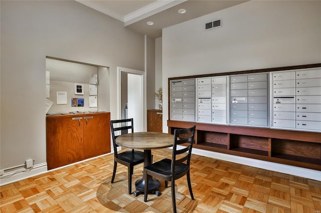 dining room with mail area, a towering ceiling, crown molding, and baseboards