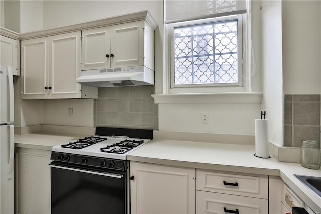 kitchen featuring under cabinet range hood, gas range, decorative backsplash, and light countertops