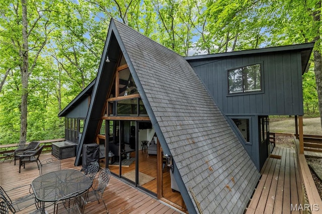 682 Shadow Lake Circle Dr, Innsbrook, MO 63390 - rear view of house with a wooden deck, outdoor dining space, roof with shingles, board and batten siding, and a sunroom