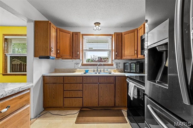 109 N Grant St, Desloge, MO 63601 - kitchen with stainless steel appliances, a sink, brown cabinets, healthy amount of natural light, and a textured ceiling