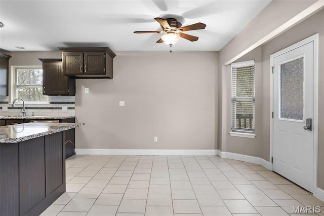 443 Mark Twain Loop, Union, MO 63084 - kitchen with a ceiling fan, light stone countertops, dark brown cabinetry, and tasteful backsplash