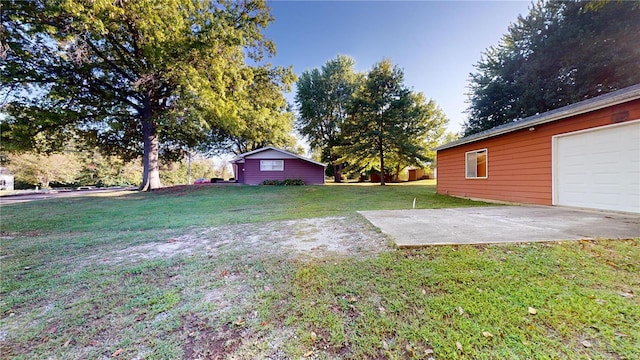 view of yard with concrete driveway and a garage