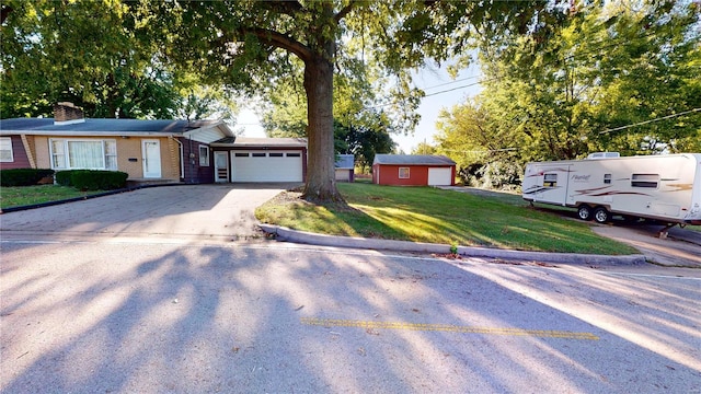 ranch-style house with a chimney, driveway, brick siding, an attached garage, and a front yard