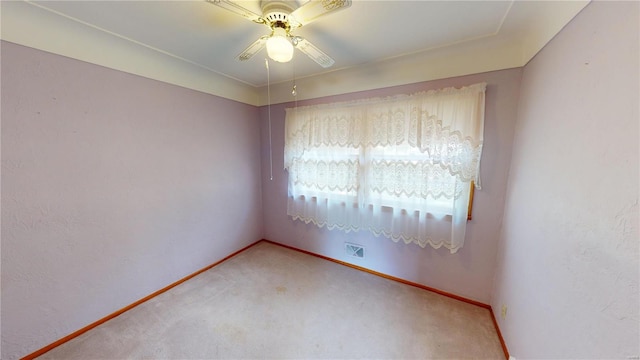 spare room with a ceiling fan, light carpet, and baseboards
