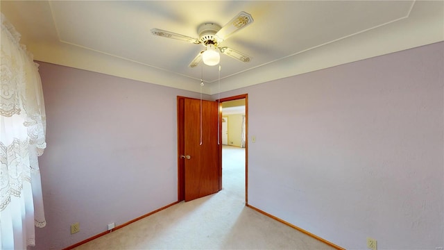 empty room featuring light colored carpet, baseboards, and a ceiling fan