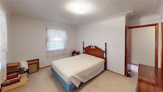 bedroom with light colored carpet and baseboards
