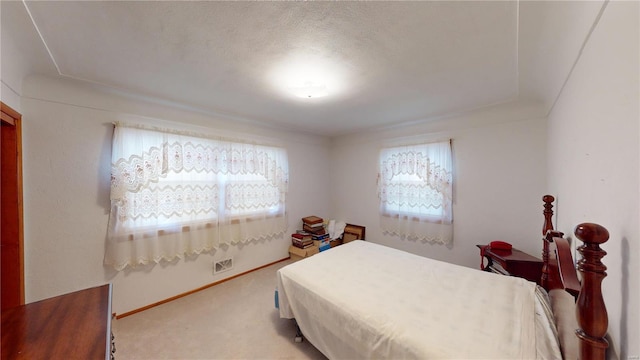 bedroom with light colored carpet, baseboards, and a textured ceiling