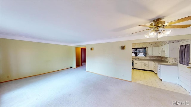 4645 S State Route 159, Glen Carbon, IL 62034 - unfurnished living room featuring a ceiling fan, ornamental molding, baseboards, light colored carpet, and a sink
