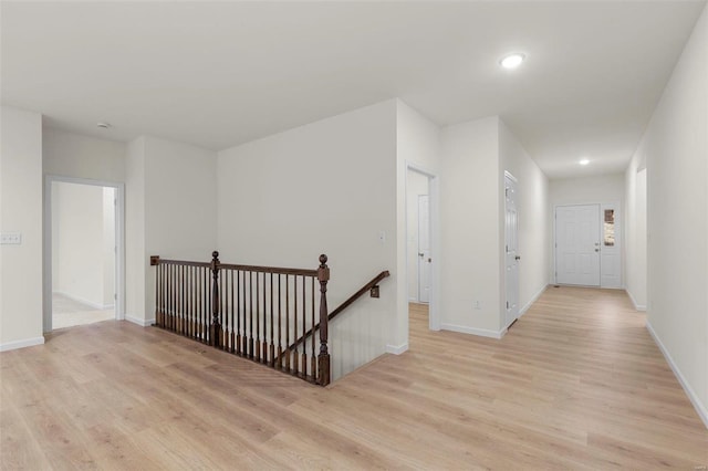 hall featuring an upstairs landing, light wood finished floors, baseboards, and recessed lighting
