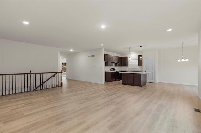 kitchen featuring open floor plan, dark brown cabinets, a center island, light countertops, and light wood-style floors