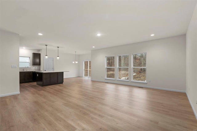 unfurnished living room with light wood finished floors, recessed lighting, and baseboards